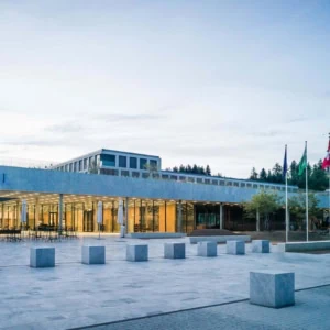 Façade moderne de lEHL au crépuscule, place vide en pierre, verre et béton.