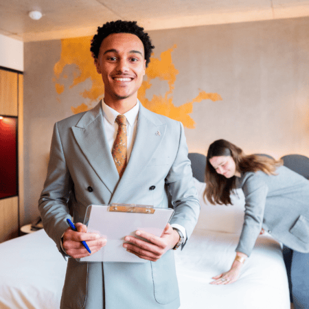 Préparation chambre dhôtel : personnel souriant, bloc-notes et lit impeccables.