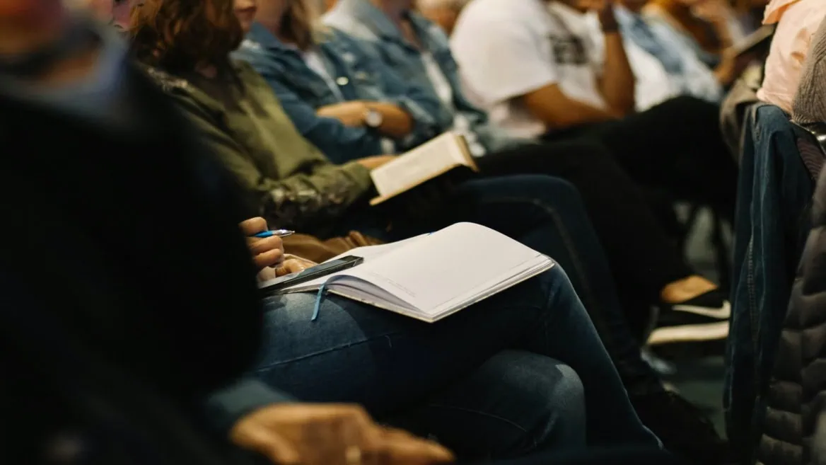 Prise de notes au séminaire : participant avec carnet, stylo et smartphone.