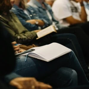 Prise de notes au séminaire : participant avec carnet, stylo et smartphone.