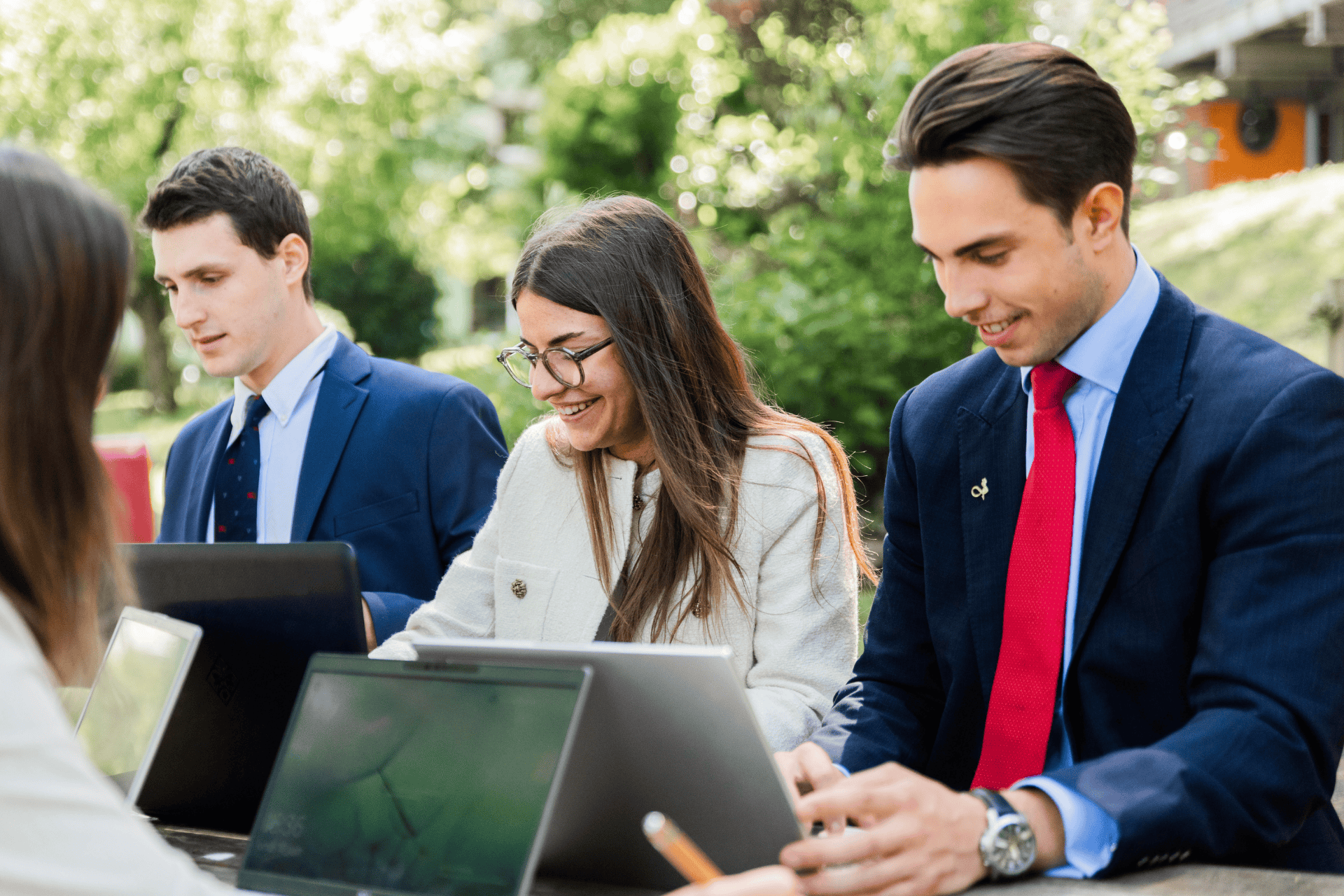 Professionnels en équipe travaillant en extérieur sur ordinateurs portables, collaboration et productivité.