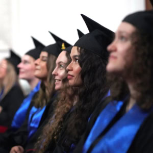 Étudiants en toges noires et écharpes bleues alignés lors dune remise de diplômes.