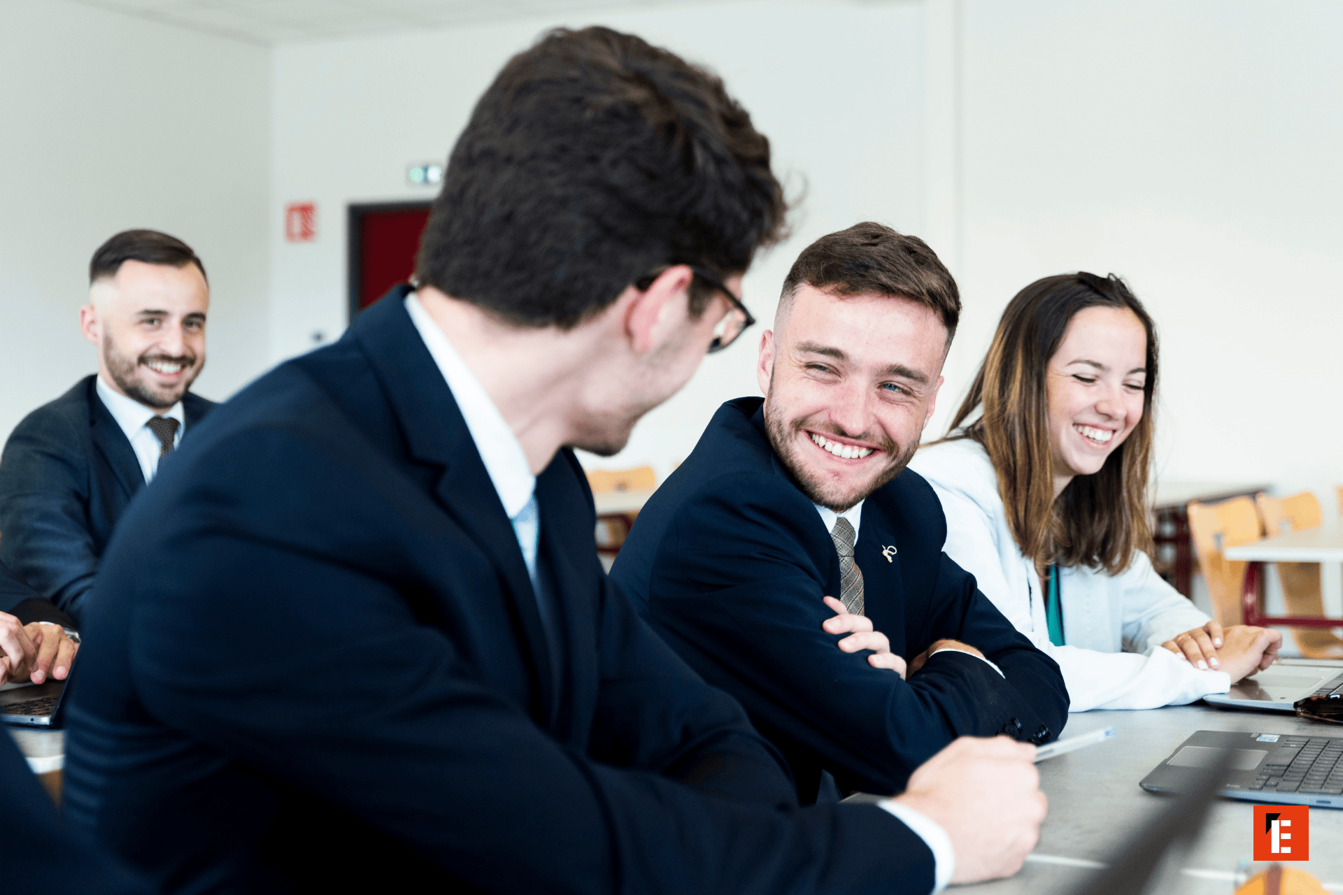 Réunion déquipe professionnelle en bureau, collègues souriants collaborant autour dun ordinateur.