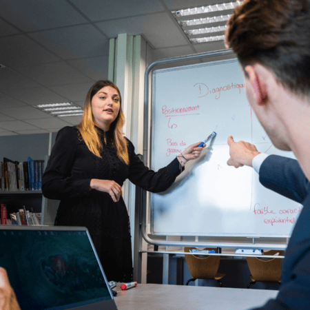 Réunion d’équipe en bureau avec tableau blanc, présentation, participants et ordinateurs.