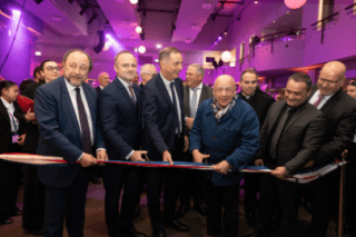 Inauguration : coupe de ruban tricolore par officiels sous éclairage violet.