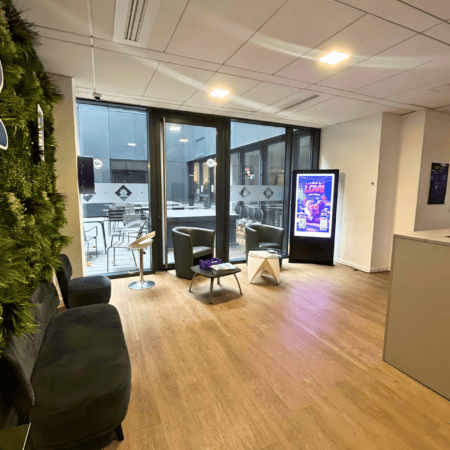Salle dattente moderne avec mobilier minimaliste, mur végétal et cour vitrée.