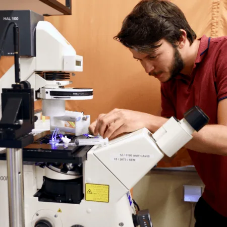 Technicien au microscope Axiovert réalisant micro-manipulation fluorescente en laboratoire.