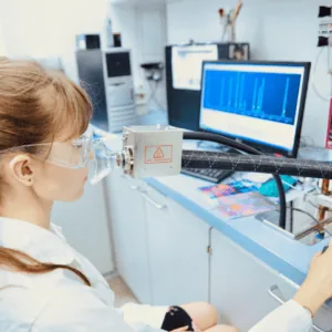 Technicienne en blouse effectuant test de respiration au laboratoire devant écran spectral danalyse.
