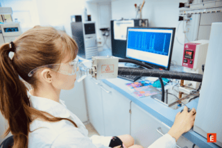 Technicienne en blouse effectuant test de respiration au laboratoire devant écran spectral danalyse.