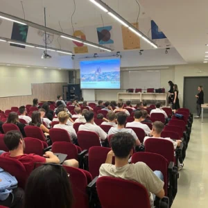 Amphithéâtre rempli détudiants pour une présentation de bienvenue et dorientation projetée.