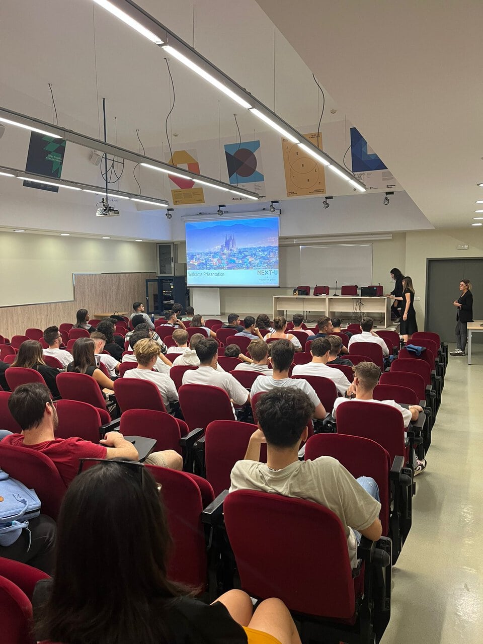 Amphithéâtre rempli détudiants pour une présentation de bienvenue et dorientation projetée.