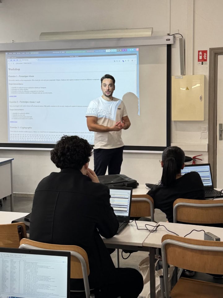 Atelier de formation en salle avec instructeur, projection et étudiants sur ordinateurs portables.