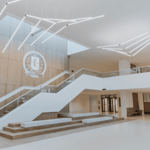 Atrium minimaliste en bois, design contemporain, escalier, mezzanine vitrée et lumière naturelle.