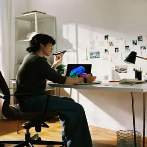 Bureau à domicile lumineux avec ordinateur portable, plantes, espace de télétravail organisé.