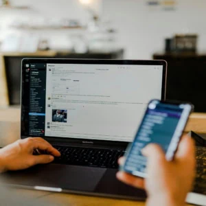 MacBook Pro au café, travail multitâche avec smartphone, carnet et café glacé.