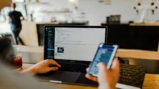 MacBook Pro au café, travail multitâche avec smartphone, carnet et café glacé.