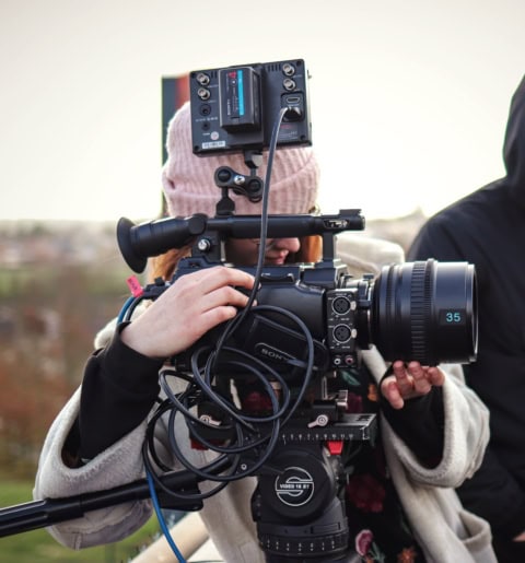Caméra professionnelle avec téléobjectif 35 mm sur trépied, opérateur concentré.