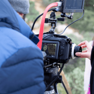 Caméra cinéma pro sur trépied, équipe de tournage ajustant le suivi de mise au point.