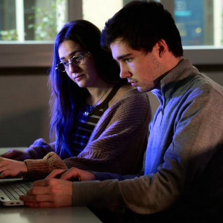 Étudiants ESGI travaillant en binôme sur ordinateurs portables dans un laboratoire informatique du campus.