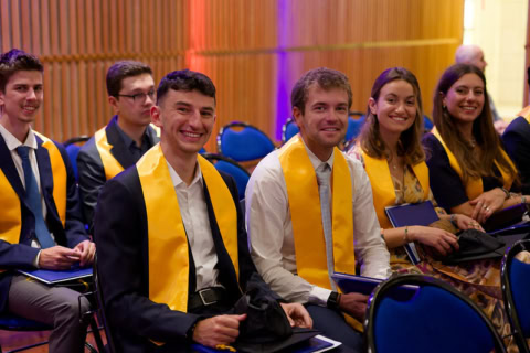 Étudiants en rangée avec écharpes dorées lors dune cérémonie de remise des diplômes.