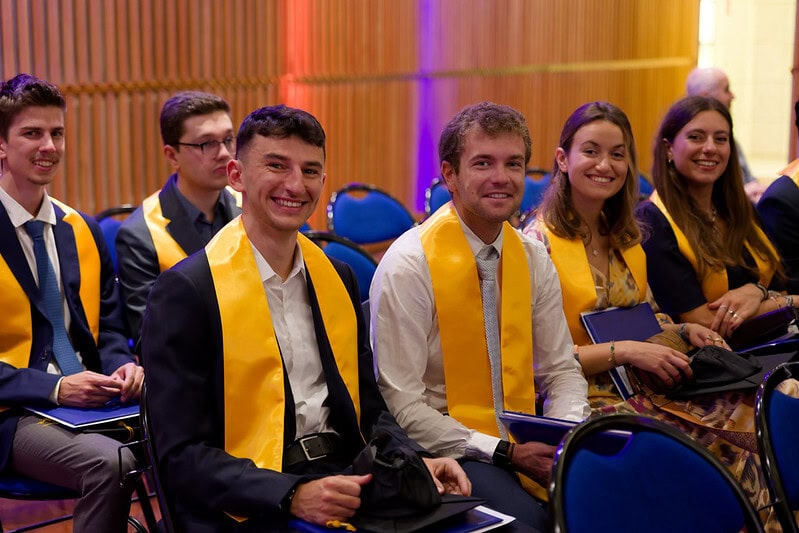 Étudiants en rangée avec écharpes dorées lors dune cérémonie de remise des diplômes.