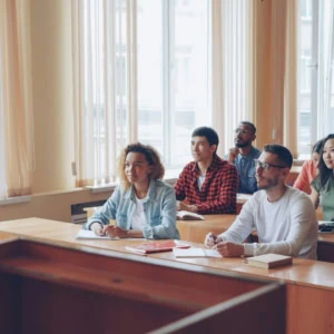 Cours universitaire en salle lumineuse avec professeur et étudiants attentifs.