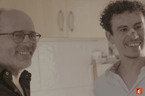 Portrait de deux hommes souriants dans une cuisine chaleureuse, photo intime et décontractée.