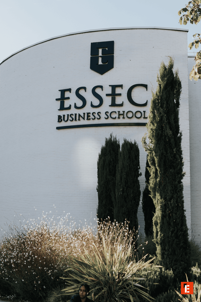 Façade blanche incurvée de lESSEC, école de commerce, logo et végétation.