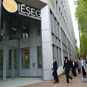 Entrée IÉSEG, école de management moderne, façade vitrée, étudiants arrivant.