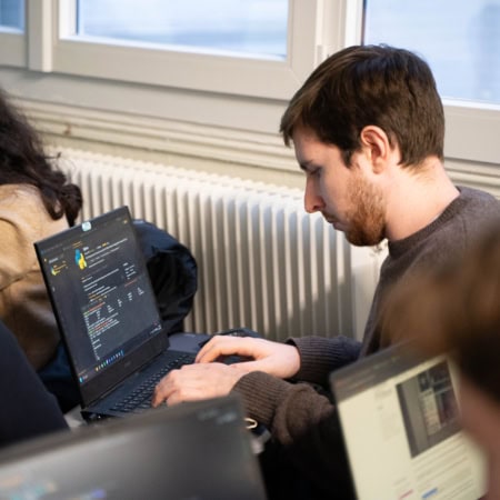 Deux personnes concentrées sur ordinateurs portables, codage Python en espace de travail collaboratif.