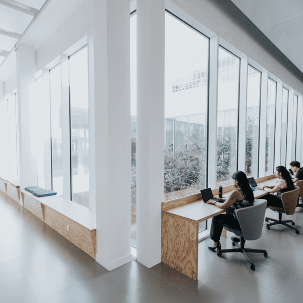 Espace de travail lumineux coworking minimaliste avec bureaux face aux fenêtres et lumière naturelle.