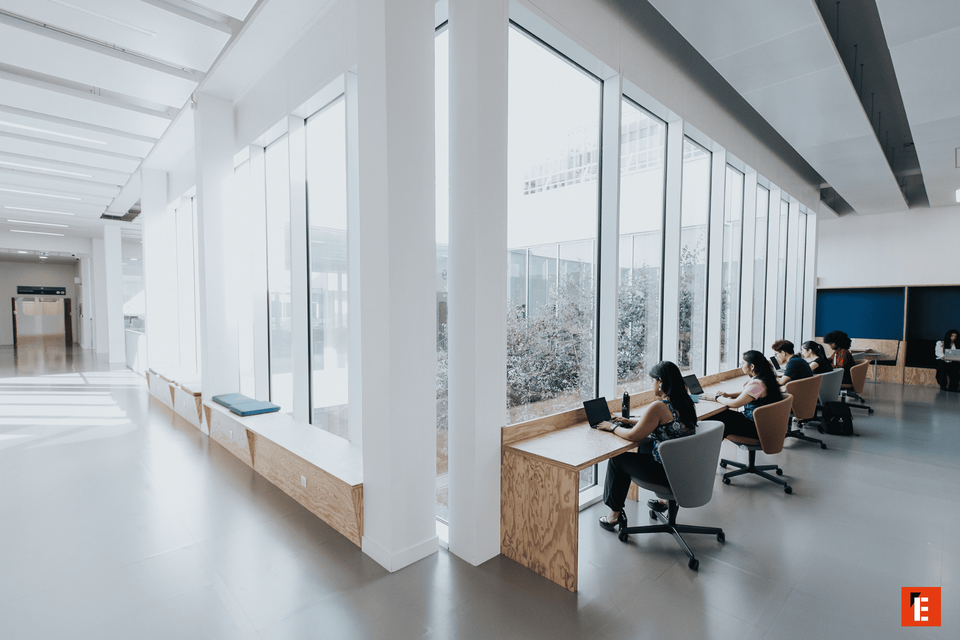 Espace de travail lumineux coworking minimaliste avec bureaux face aux fenêtres et lumière naturelle.