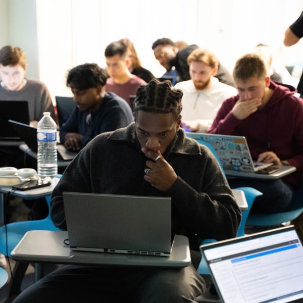 Étudiants concentrés en classe sur ordinateurs portables, salle détude collaborative moderne.