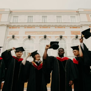 Étudiants diplômés lancent leurs birets devant un bâtiment universitaire historique.