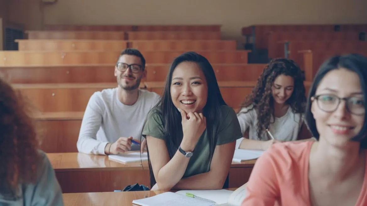 Étudiants souriants en amphi en bois à luniversité, prise de notes studieuse.