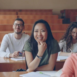 Étudiants souriants en amphi en bois à luniversité, prise de notes studieuse.