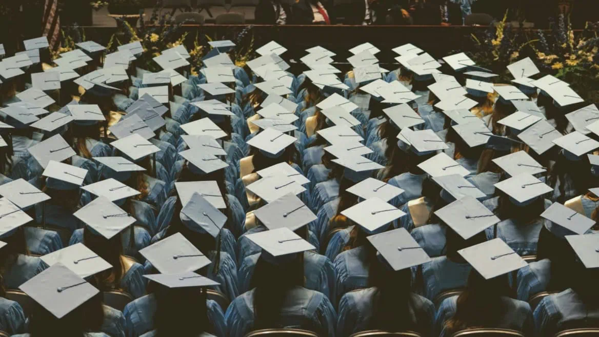 Remise des diplômes : foule détudiants en toques et robes bleues vue de dos.