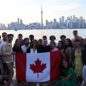 Groupe damis brandissant drapeau canadien devant la skyline de Toronto au bord de leau.