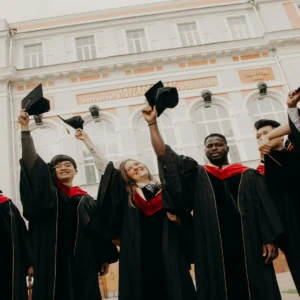 Étudiants diplômés lançant leurs toques devant un bâtiment universitaire classique.