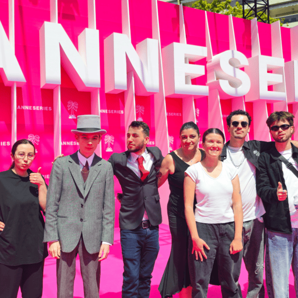 Groupe de neuf personnes devant un mur photo fuchsia de festival, portrait en plein soleil.