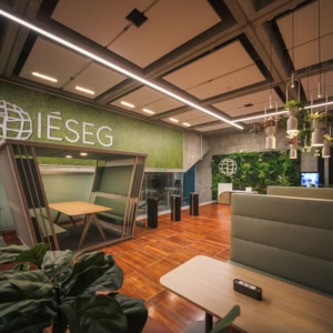 Lobby IESEG contemporain avec mur végétal, réception, banquettes et tourniquets.