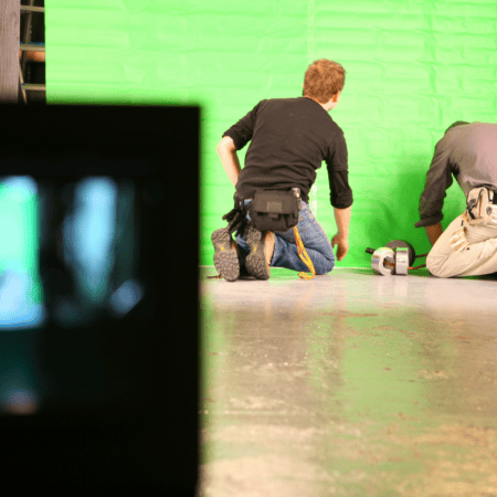 Techniciens installant un écran vert sur le plateau de tournage en studio.