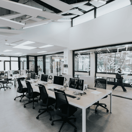 Laboratoire informatique lumineux moderne avec rangées dordinateurs, postes de travail ergonomiques et cloisons vitrées.