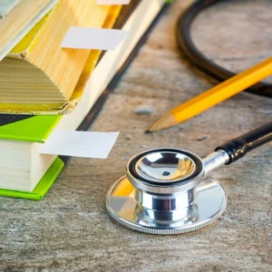 Livres et stéthoscope sur bureau en bois, crayon, étude médicale.