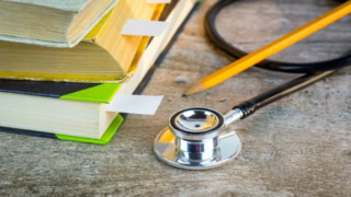 Livres et stéthoscope sur bureau en bois, crayon, étude médicale.