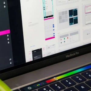 MacBook Pro écran montrant maquettes dinterface utilisateur et design, Touch Bar visible.