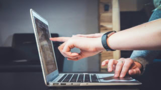 Mains pointant écran dordinateur portable, collaboration et travail sur clavier.