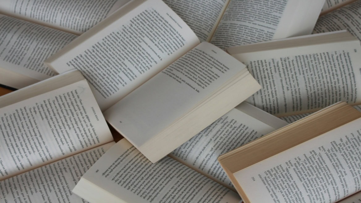 Pages de livres ouverts en éventail, textes imprimés sur papier crème et jauni, ambiance lecture.