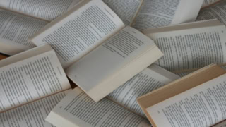 Pages de livres ouverts en éventail, textes imprimés sur papier crème et jauni, ambiance lecture.