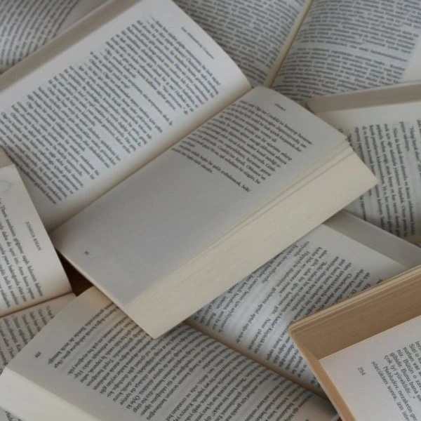 Pages de livres ouverts en éventail, textes imprimés sur papier crème et jauni, ambiance lecture.